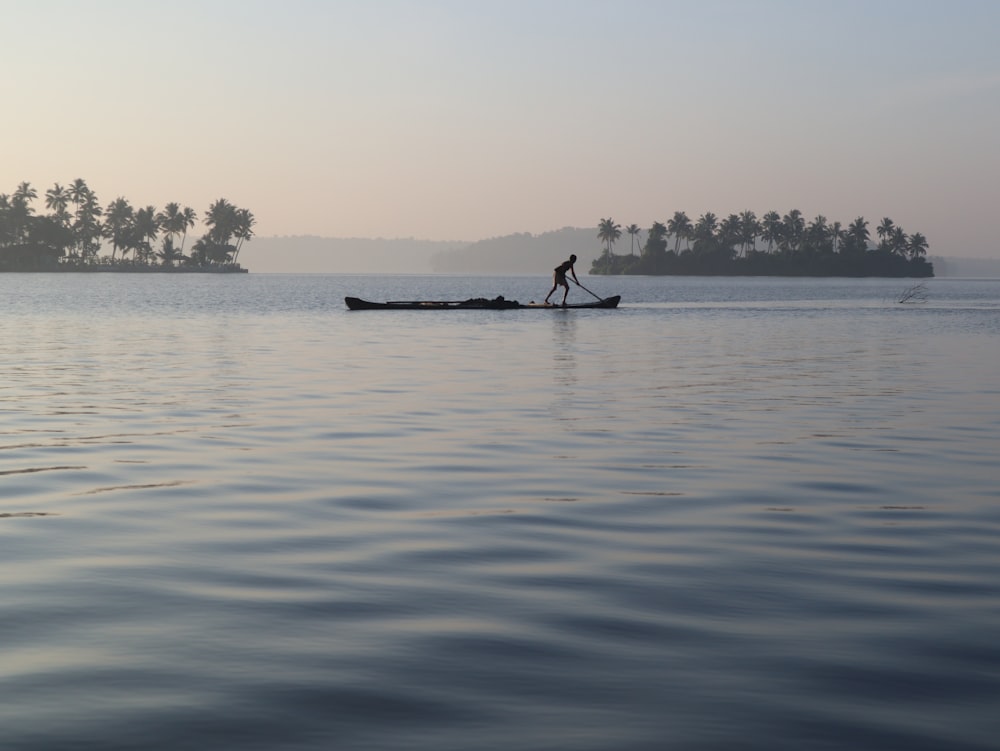 silhouette of 2 people riding on boat on sea during daytime