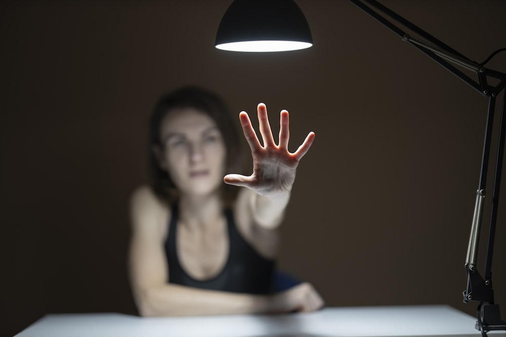 femme en débardeur noir levant les mains