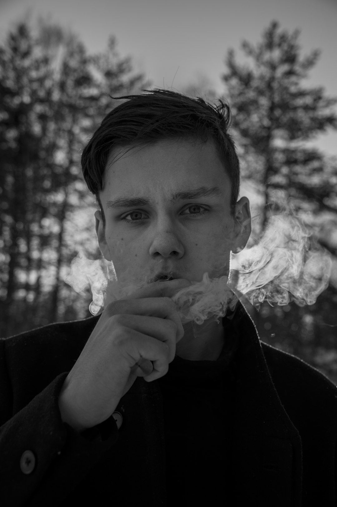 grayscale photo of man in black long sleeve shirt smoking