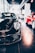 A sleek black sports car is prominently displayed indoors, surrounded by other luxury vehicles. The environment suggests a high-end showroom or dealership with bright lighting and modern architecture. The flooring is reflective, adding to the luxurious tone.