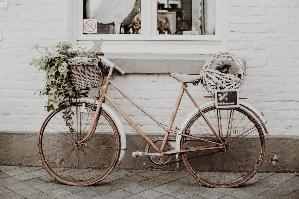 brown city bike parked beside white concrete wall