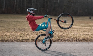 man in red jacket riding blue bmx bike