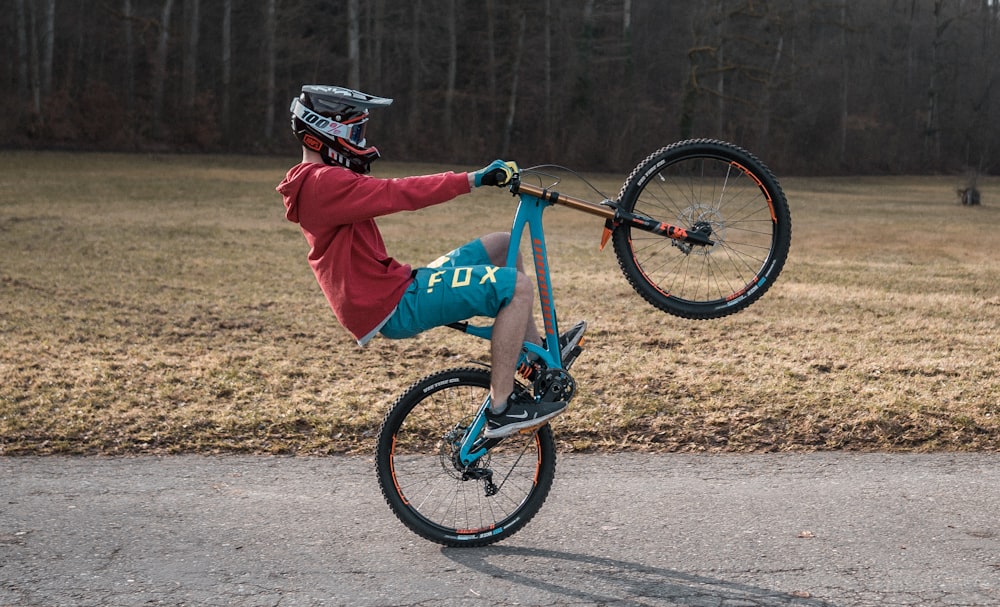 man in red jacket riding blue bmx bike