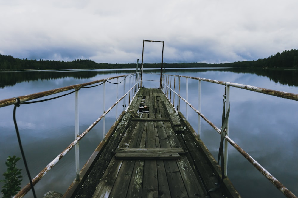 brown wooden dock over body of water under cloudy sky during daytime