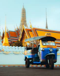 A comfortable luxury coach parked near a historic temple, ready for a spiritual tour.