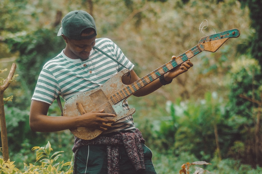 man in white and black stripe shirt playing brown electric guitar