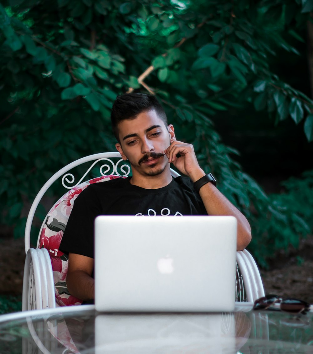 man in black and white crew neck t-shirt sitting on white and red chair