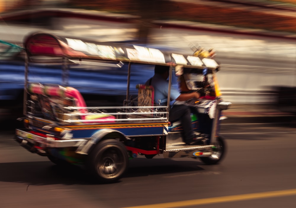 people riding on red and yellow auto rickshaw on road during daytime