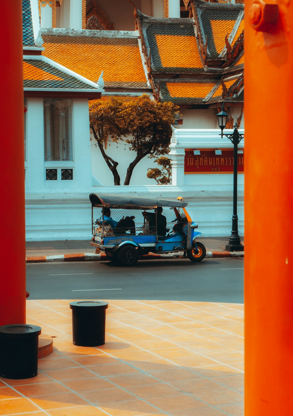 red and black auto rickshaw parked beside white building during daytime