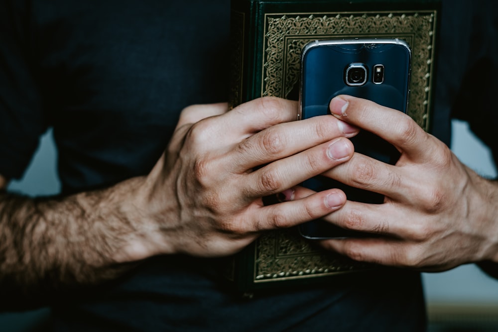 Person mit schwarz-grauem Smartphone