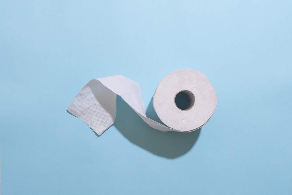 rollo de papel higiénico blanco sobre mesa blanca
