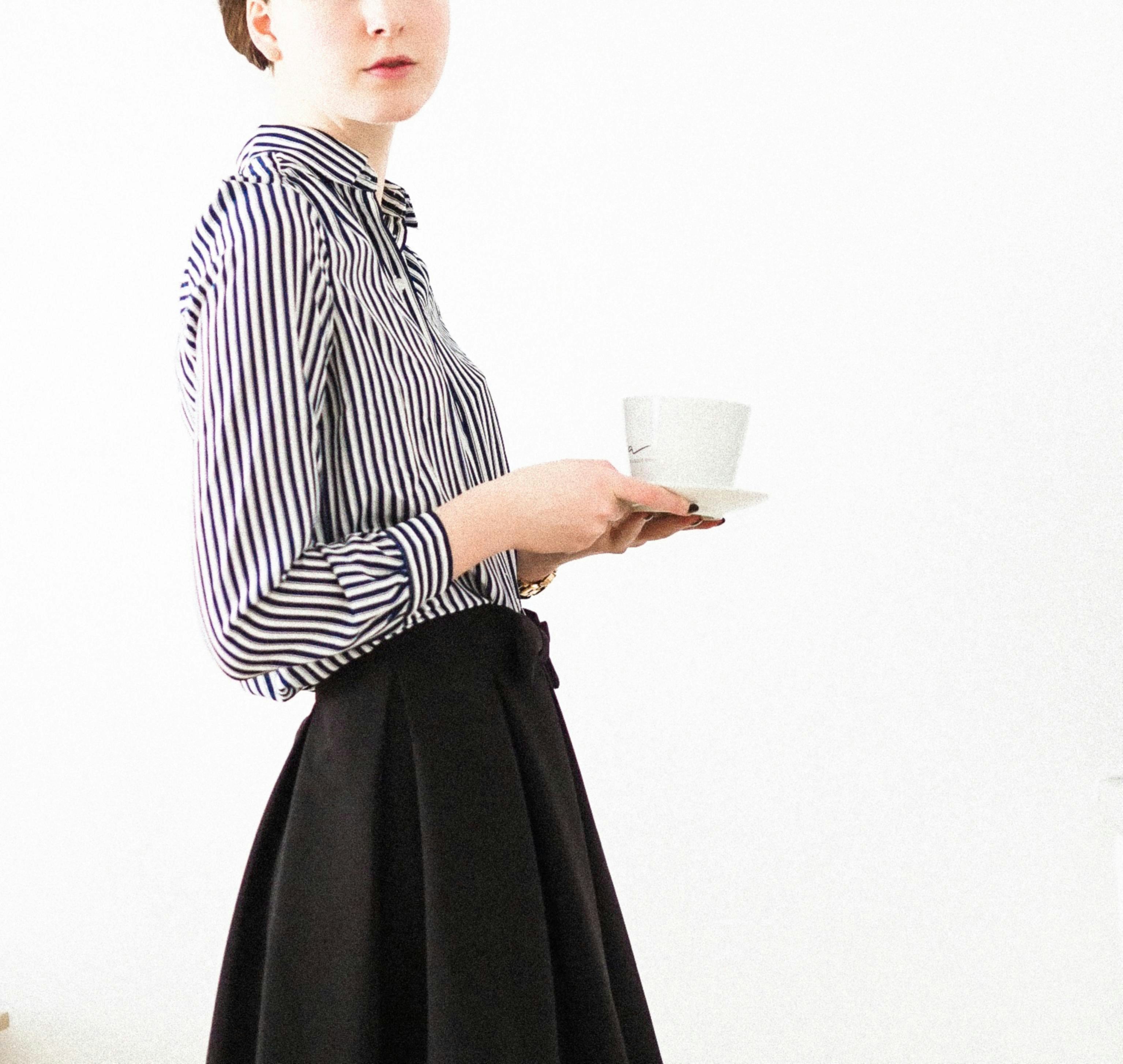 woman in black and white stripe long sleeve shirt holding white ceramic mug