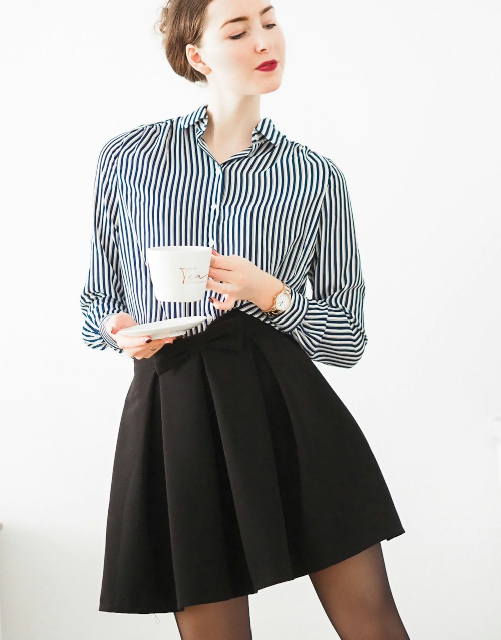 woman in black and white striped long sleeve dress holding white ceramic mug