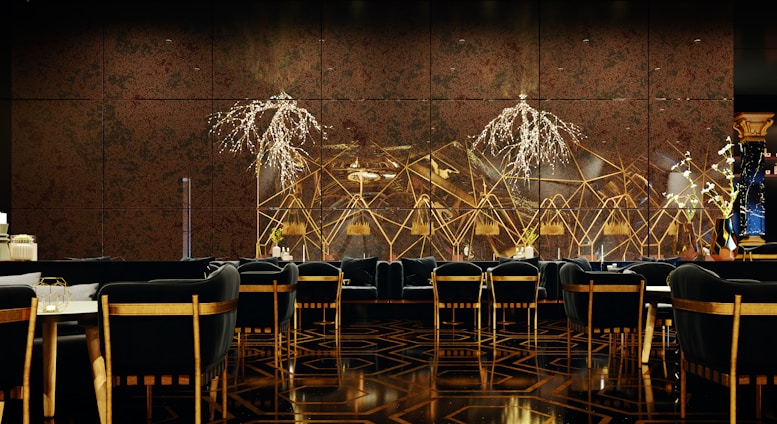 A luxurious and sophisticated interior space featuring elegant dining tables and chairs with black upholstery and wooden accents. The walls have a reflective, geometric design with intricate, illuminated floral decorations. The floor showcases a polished, patterned surface, contributing to the high-end atmosphere.