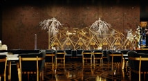 A luxurious and sophisticated interior space featuring elegant dining tables and chairs with black upholstery and wooden accents. The walls have a reflective, geometric design with intricate, illuminated floral decorations. The floor showcases a polished, patterned surface, contributing to the high-end atmosphere.