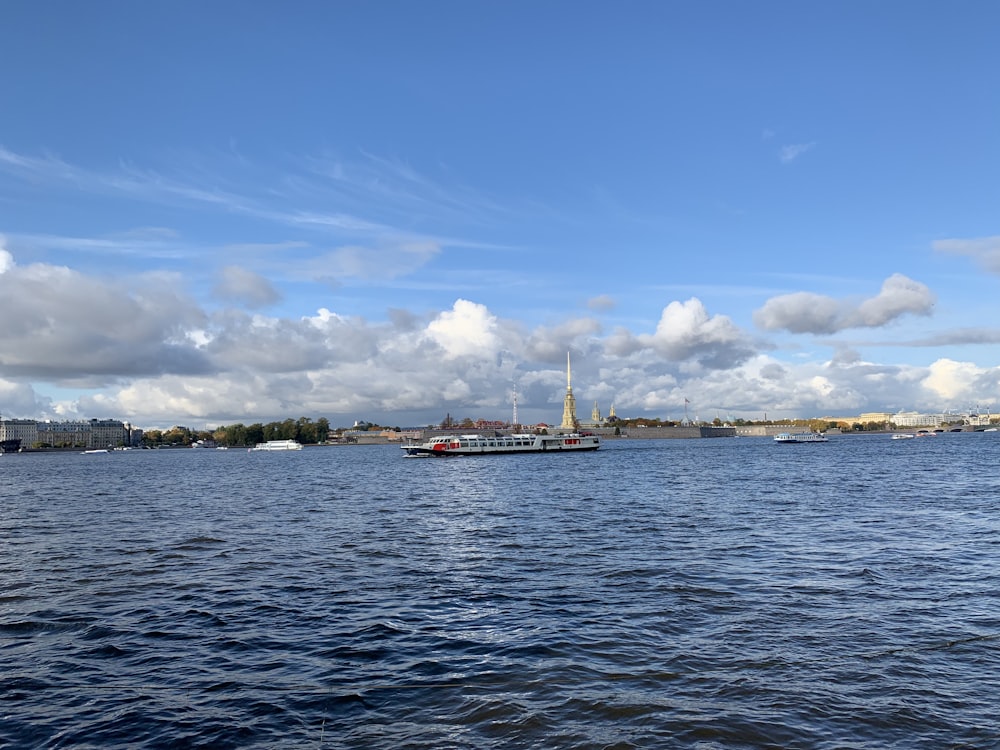 white and red boat on sea under blue sky and white clouds during daytime