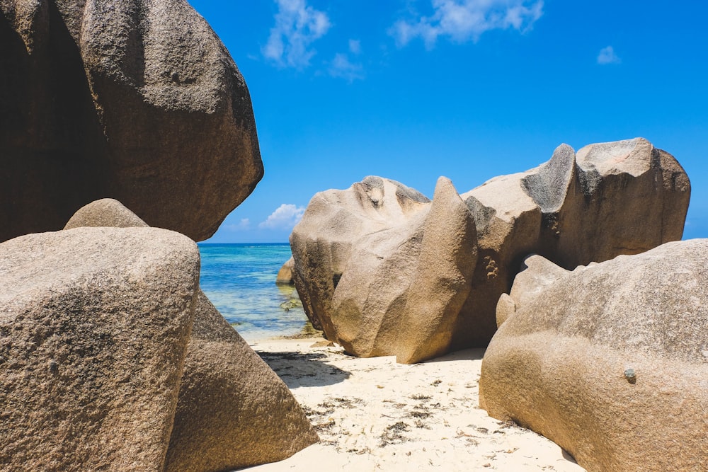 Formación de rocas grises en arena blanca cerca del cuerpo de agua durante el día