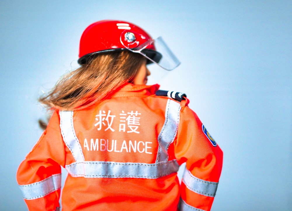 woman in orange and white jacket wearing red and white cap