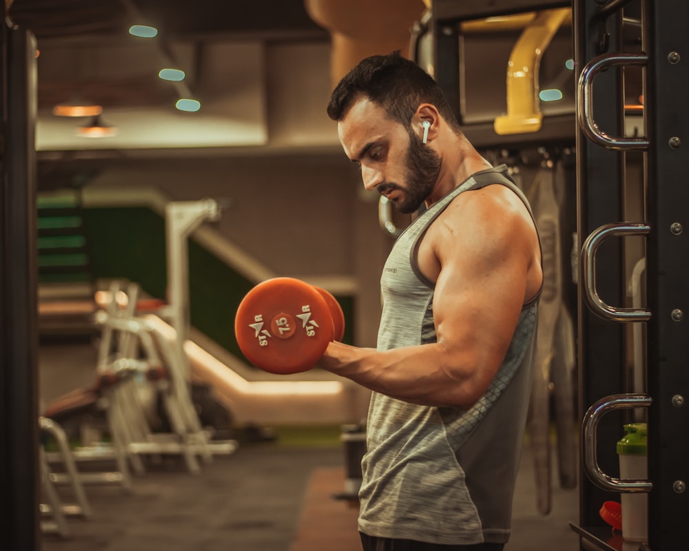 man in gray tank top holding red ball