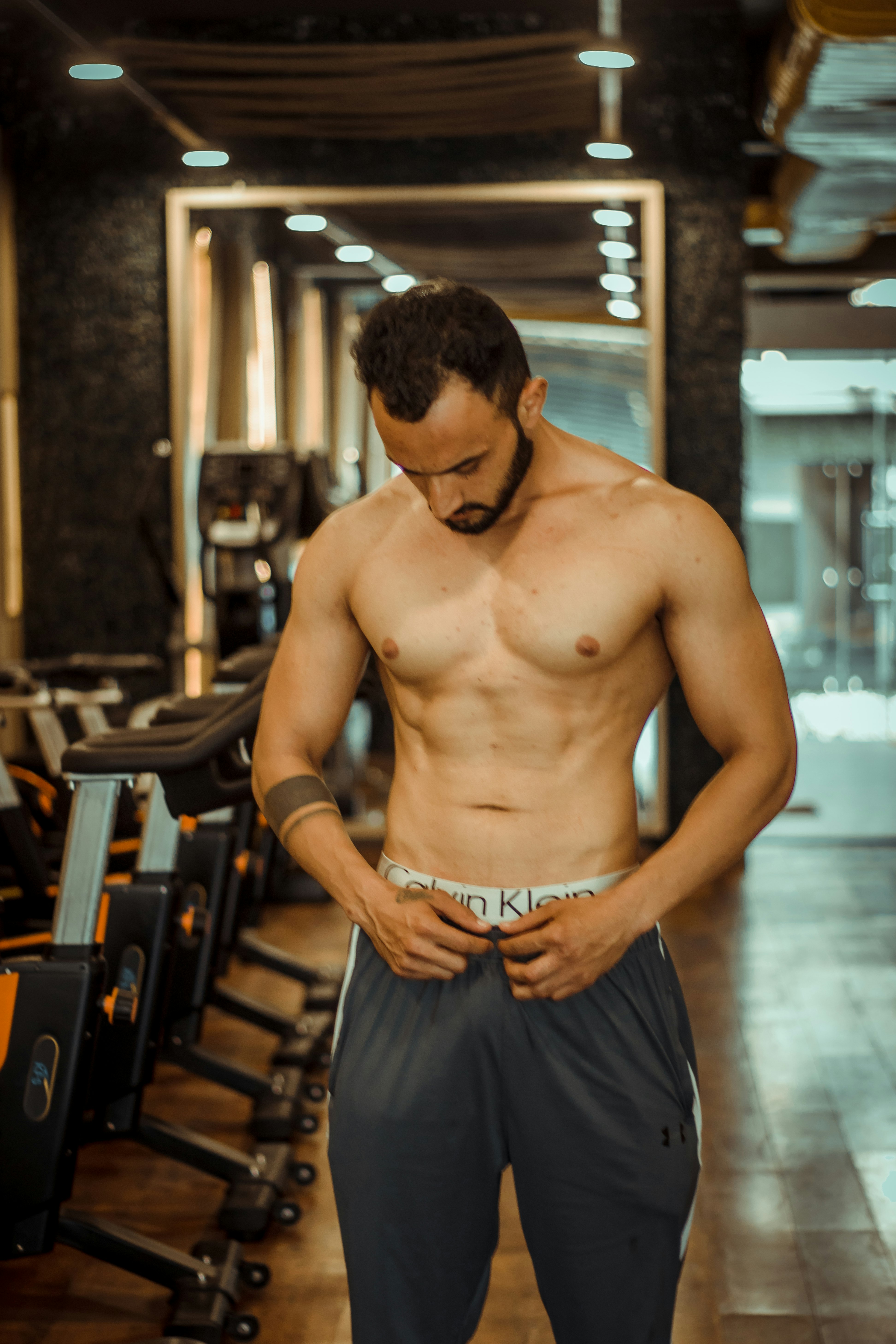 topless man in black shorts standing on brown wooden floor