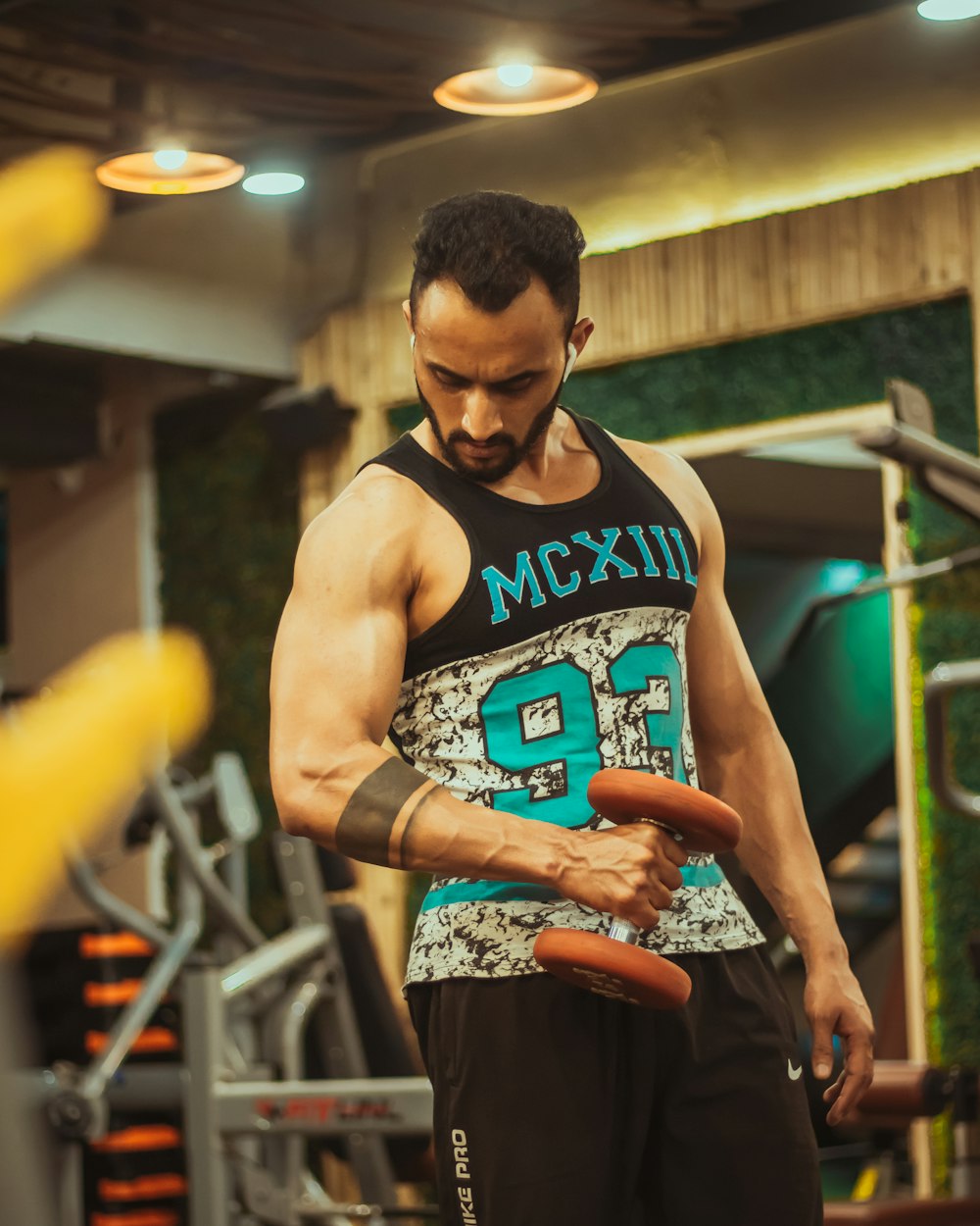 man in black tank top holding orange plastic container