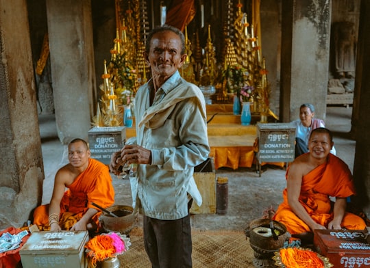 man in white robe holding a food in Angkor Wat Cambodia