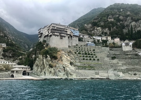 white and brown concrete building near body of water during daytime in Ιερά Μονή Διονυσίου Greece