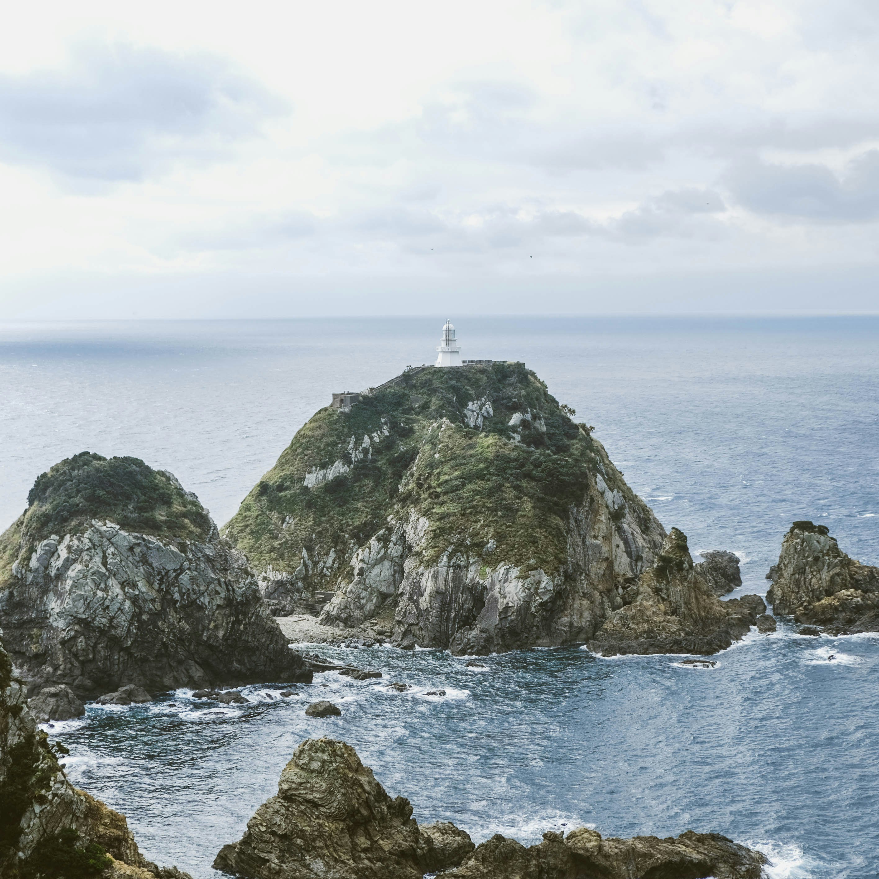 white lighthouse on top of gray rock formation near body of water during daytime