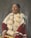 A person is adorned in traditional attire with intricate beadwork and distinctive patterns. The clothing features bright colors, including red and white with detailed decorations. The individual has long hair styled with accessories and appears poised and dignified.
