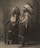 Two individuals are wearing traditional Native American clothing, including feathered headdresses, standing side by side. One holds a rifle, while both have a calm and dignified expression. The image is sepia-toned, giving it a historical feel.