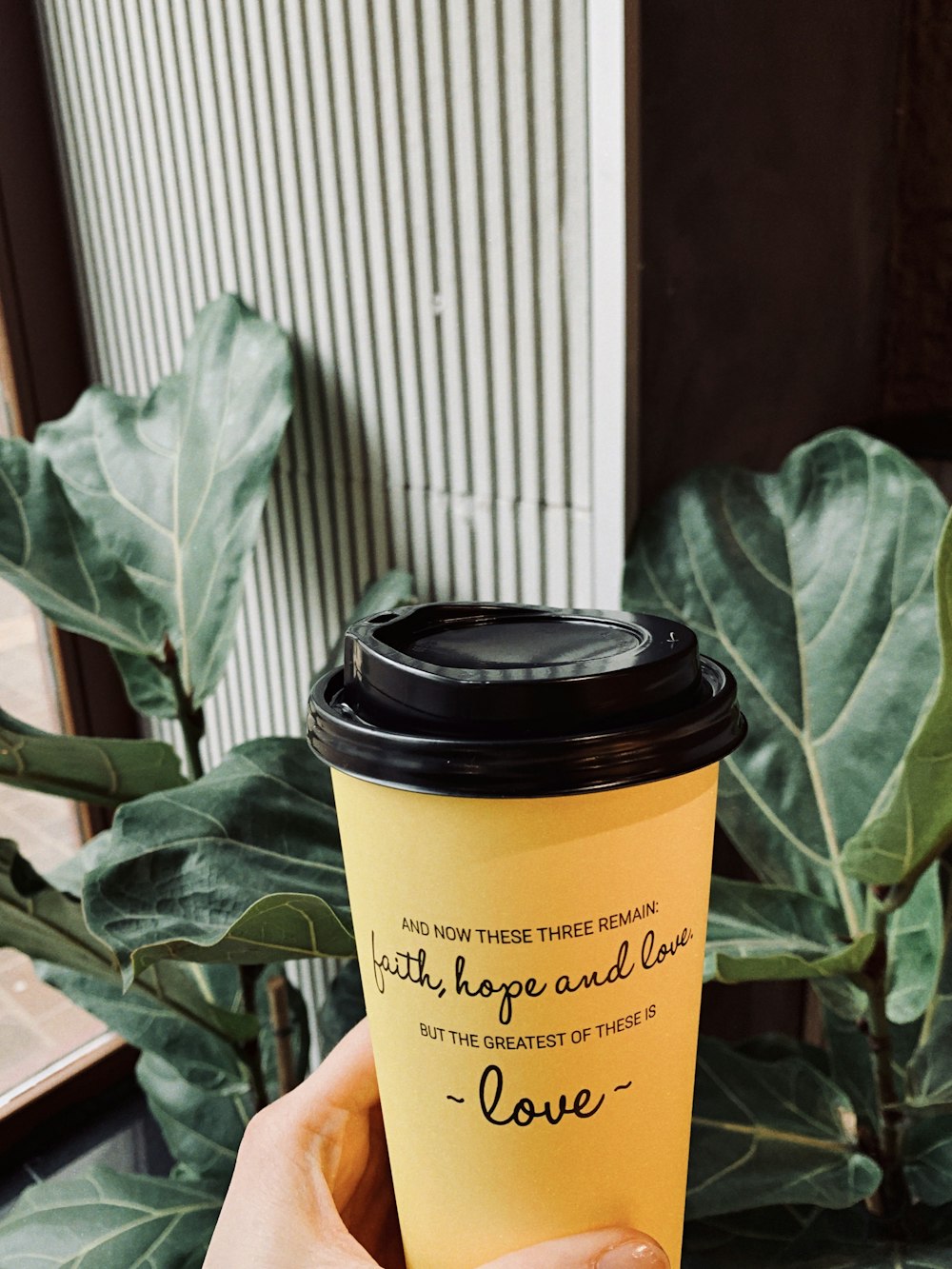 a person holding a coffee cup with a quote on it
