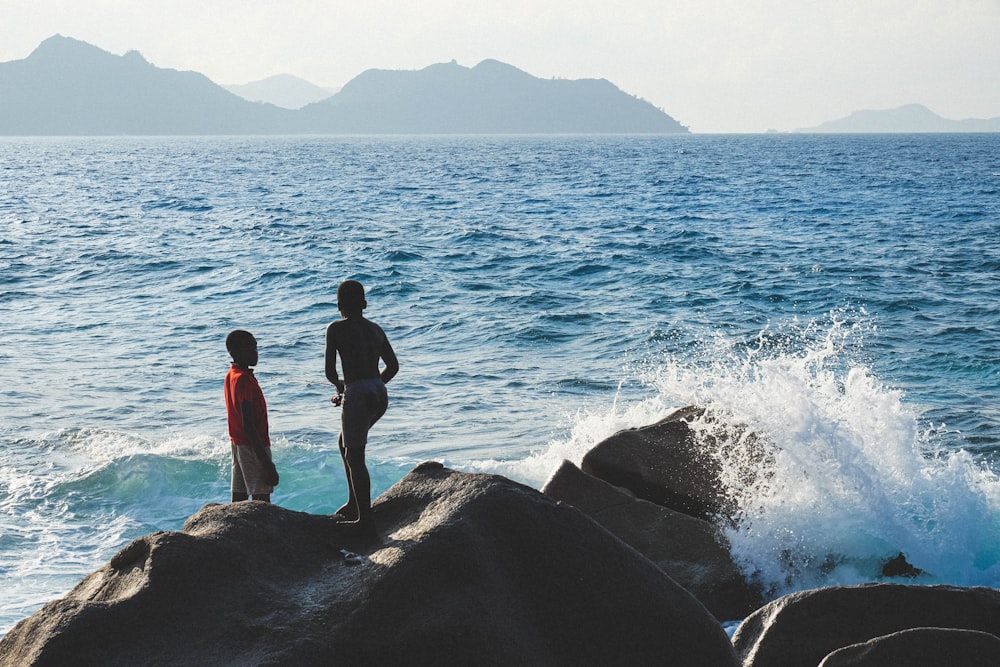 man in black shorts standing on rock near body of water during daytime