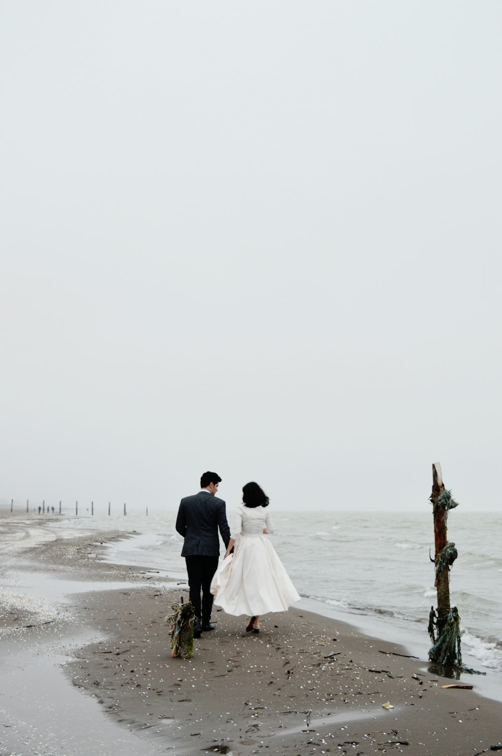 man and woman walking on beach during daytime