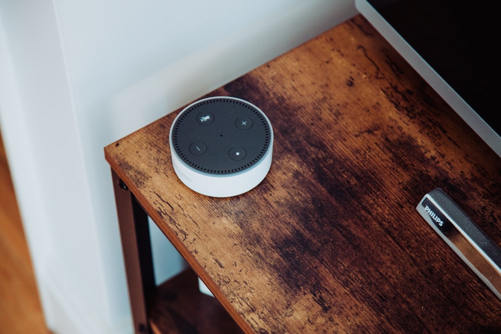 white and black amazon echo dot on brown wooden table