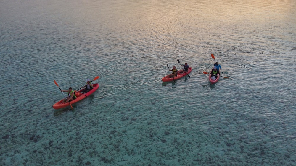 2 person riding on red kayak on body of water during daytime