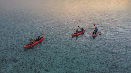 2 person riding on red kayak on body of water during daytime in Thulusdhoo Maldives