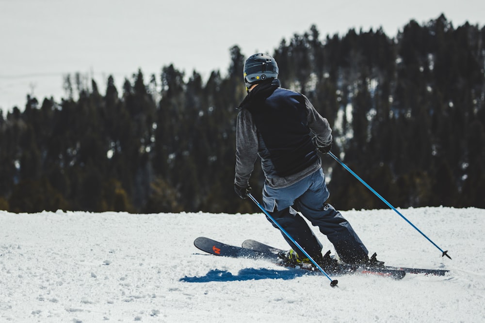 man in black jacket and blue pants riding red snowboard on snow covered ground during daytime