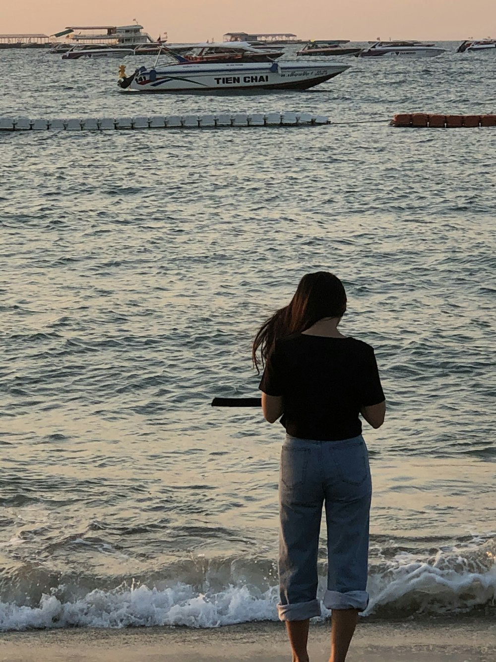 woman in black shirt and gray denim jeans standing on seashore during daytime