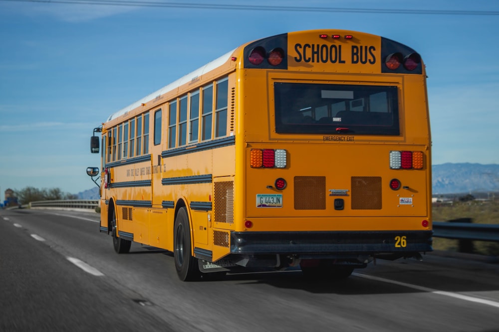 日中の道路を走る黄色いスクールバス