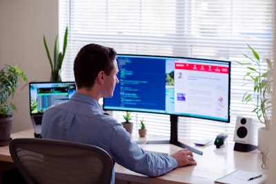 Jakie są korzyści z modernizacji strony internetowej? - man in gray dress shirt sitting on chair in front of computer monitor