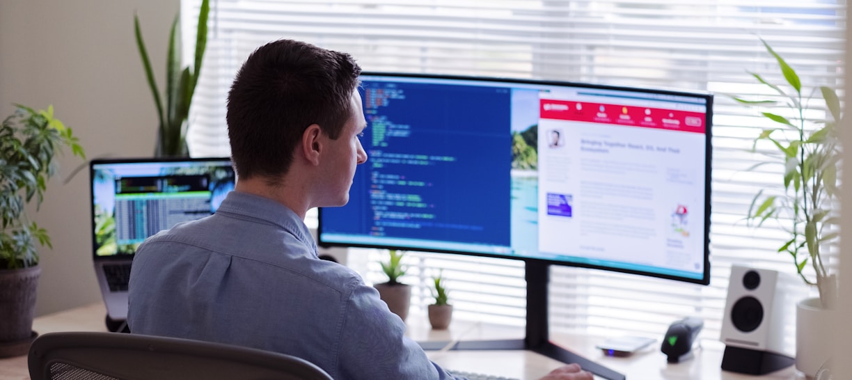 man in gray dress shirt sitting on chair in front of computer monitor