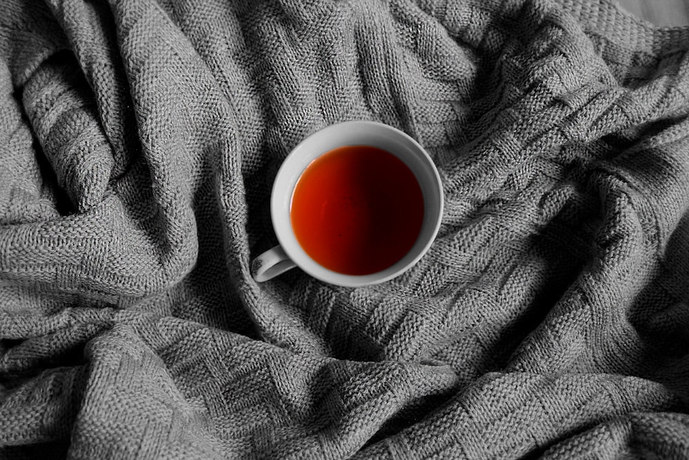 white ceramic mug on gray textile