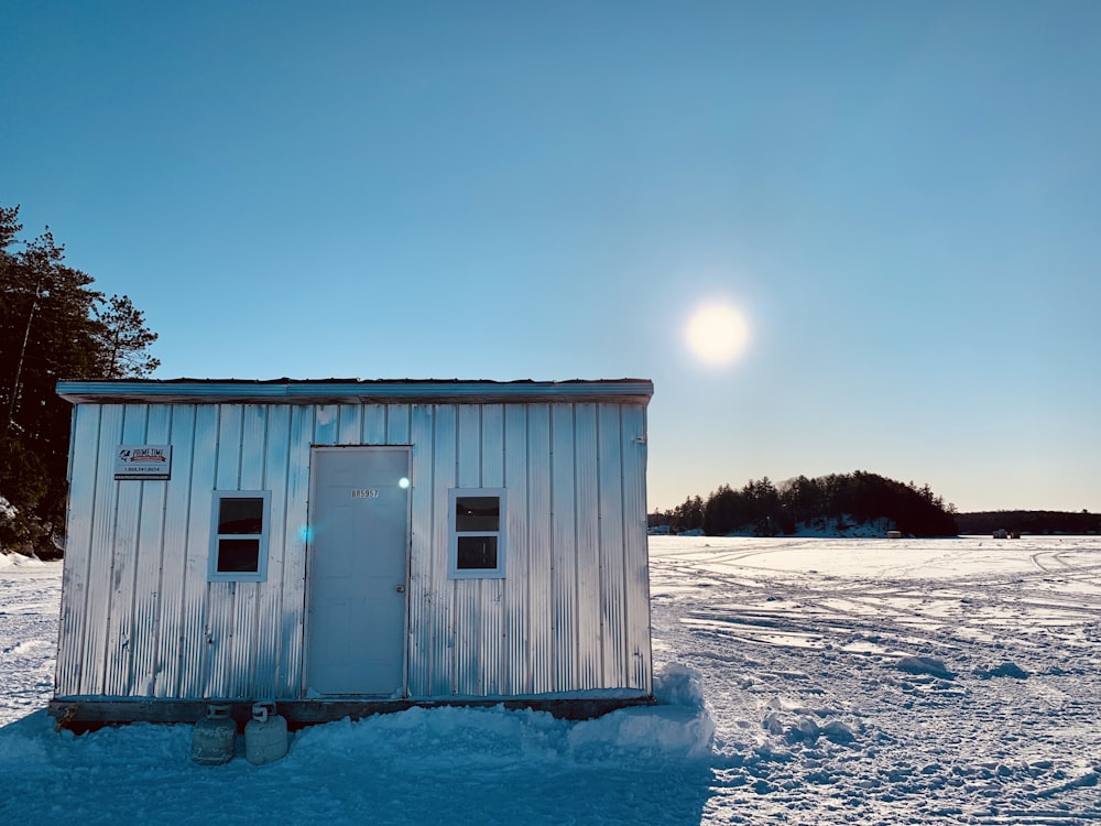 Maison en bois blanc sur un sol enneigé pendant la journée