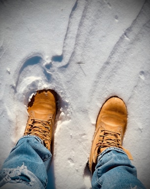 person in blue denim jeans and brown hiking shoes