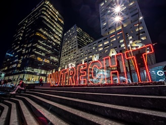 red and white train rail in between high rise buildings during nighttime