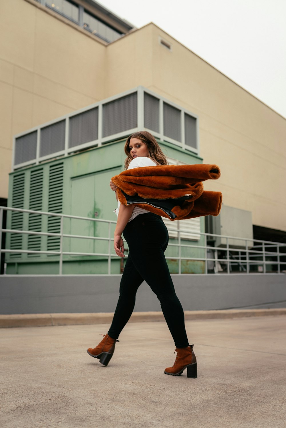 Femme en leggings noirs et chemise orange marchant sur un sol en béton gris pendant la journée