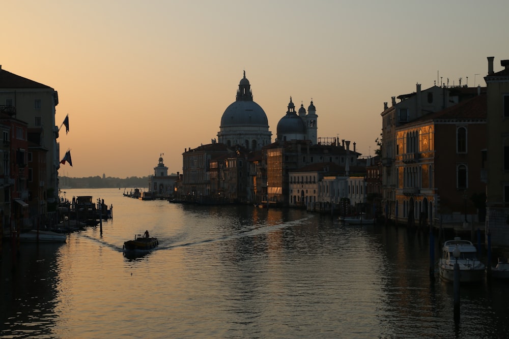 people riding boat on river near building during sunset