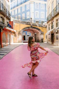 Vibrant photo of a joyful Black woman dancing on a colorful city street.