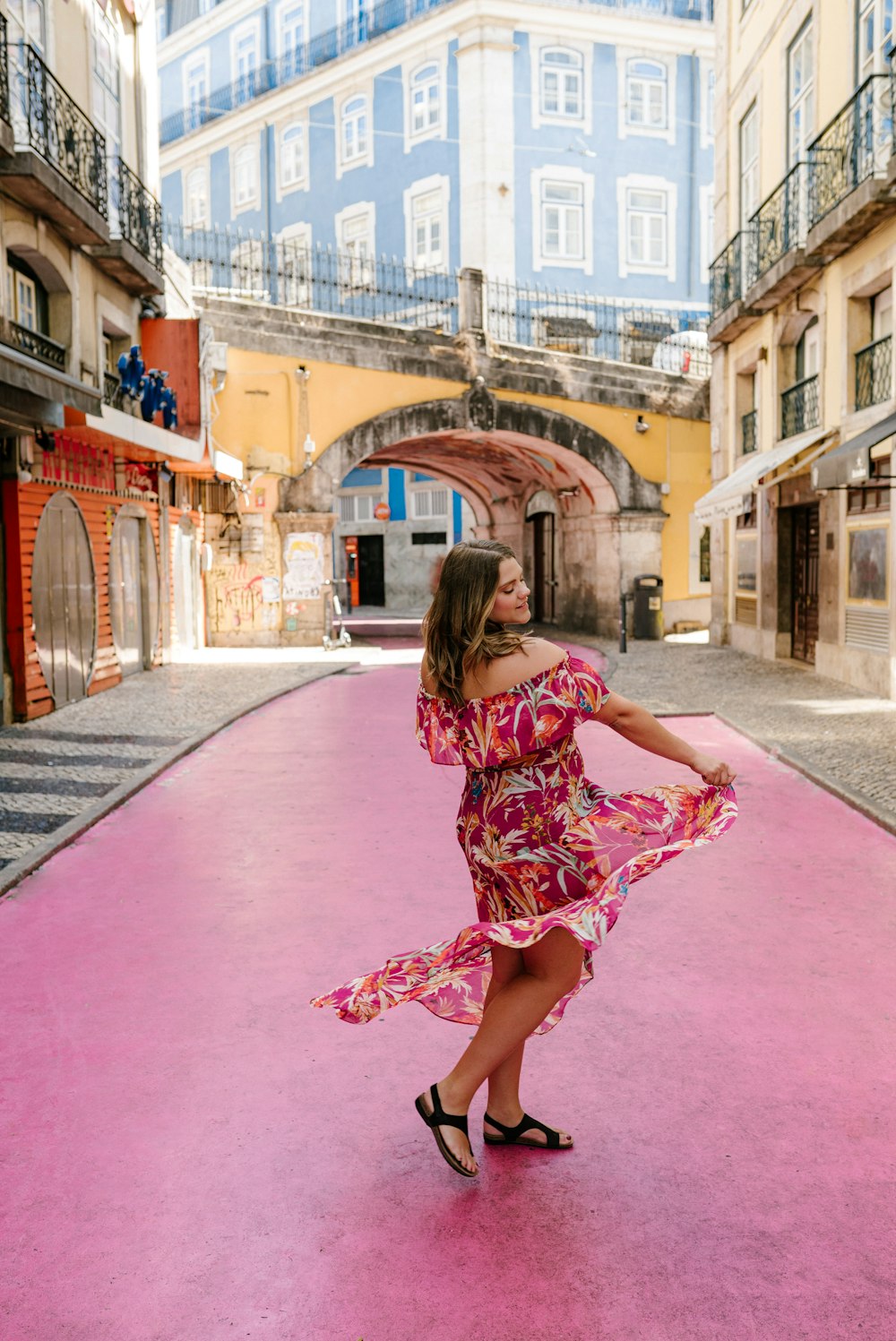 Mujer en vestido rojo, blanco y negro caminando por el camino de concreto rojo durante el día