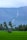 green grass field with green trees and mountain in distance